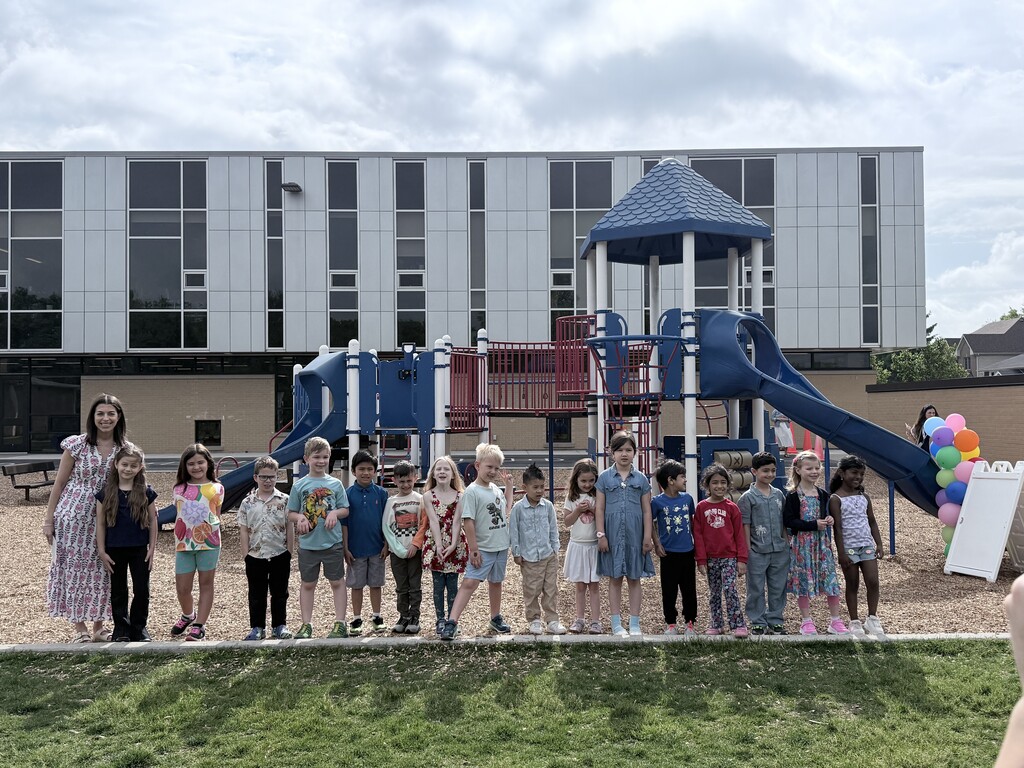 New first graders pose in front of the slide on the playground after "sliding into first grade"