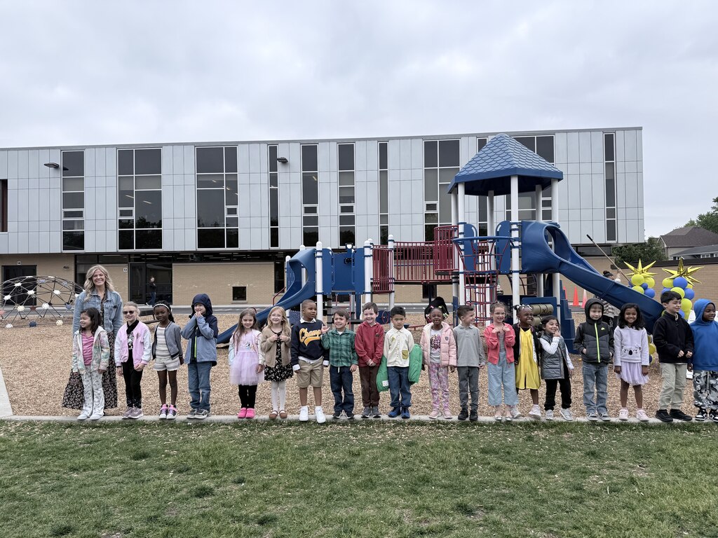 New first graders pose in front of the slide on the playground after "sliding into first grade"