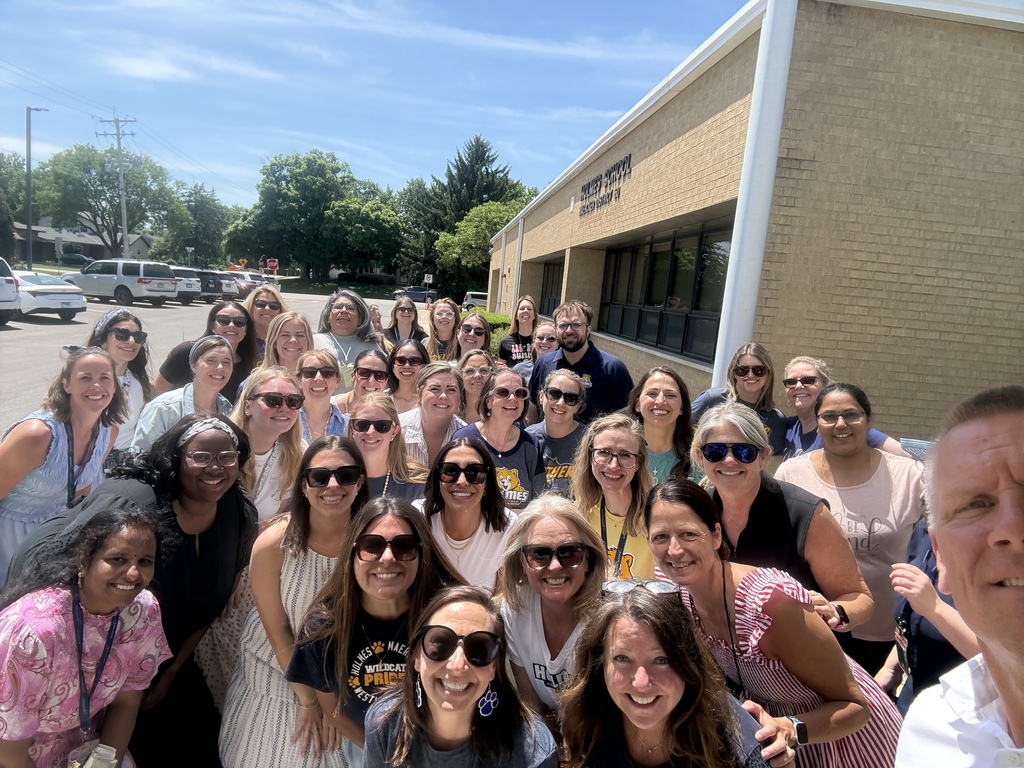 Holmes School staff smile for the camera in front of the building
