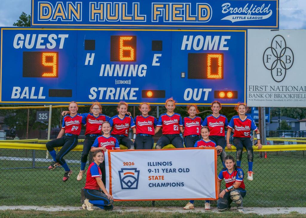 The whole team poses and smiles with a sign that reads, "Illinois 9-11 year old state champions"