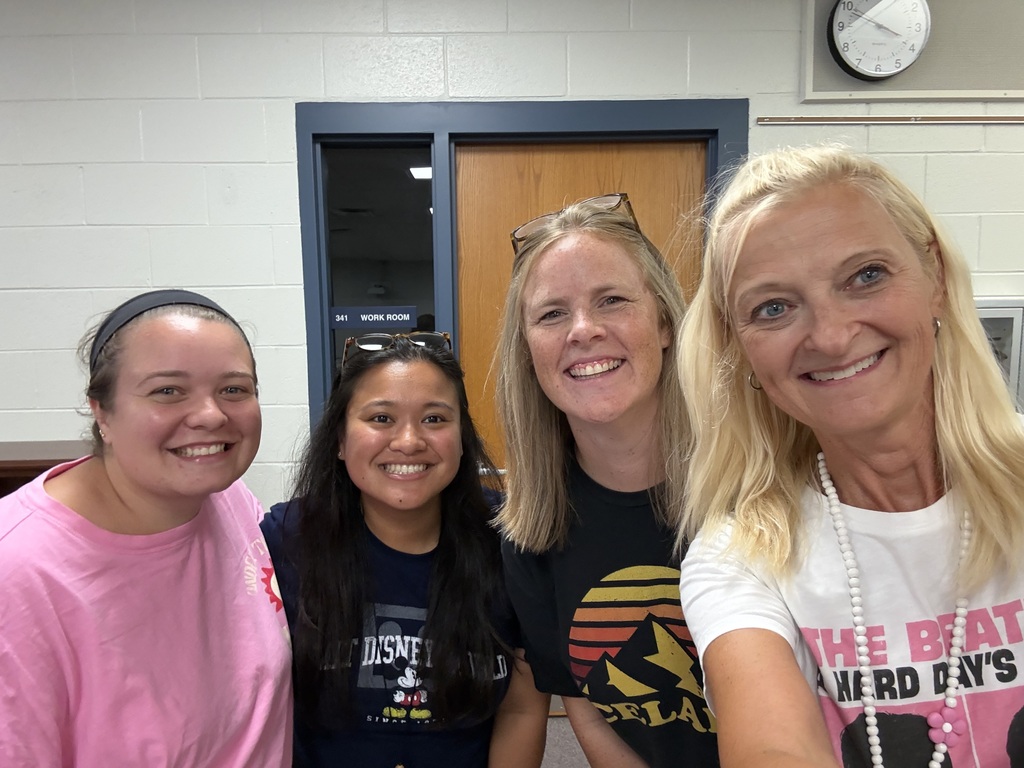 Teachers pose together and smile after organizing books
