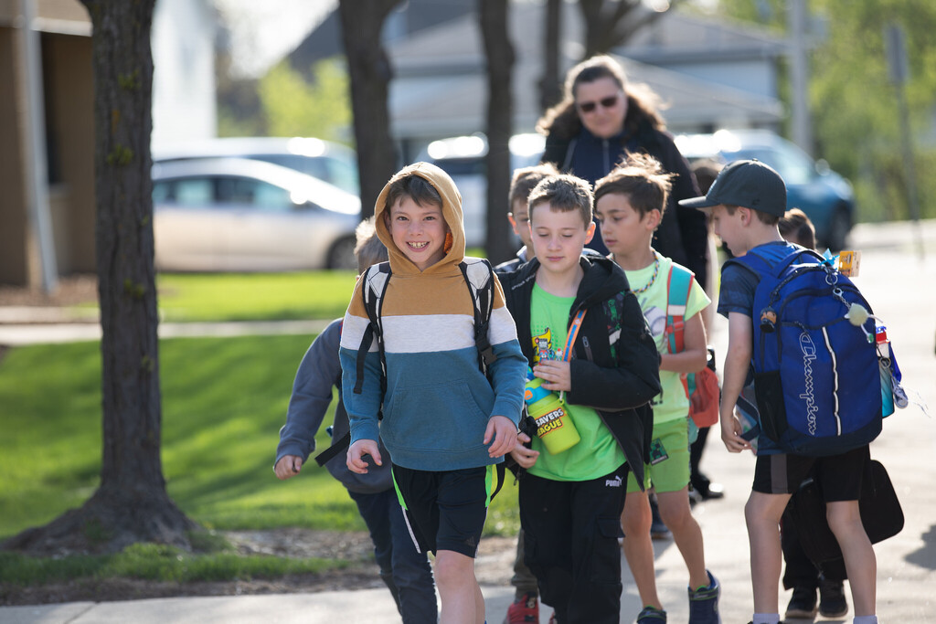 Students walk into school with one kid smiling at the camera