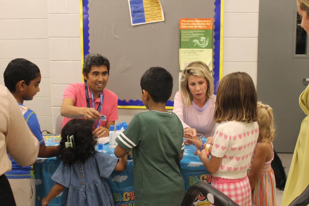 Staff and students interact and smile at a table station