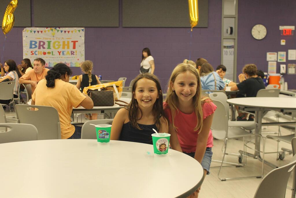 Two students pose together and smile in the cafeteria