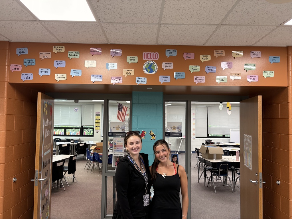 Teachers smile with wall art behind them