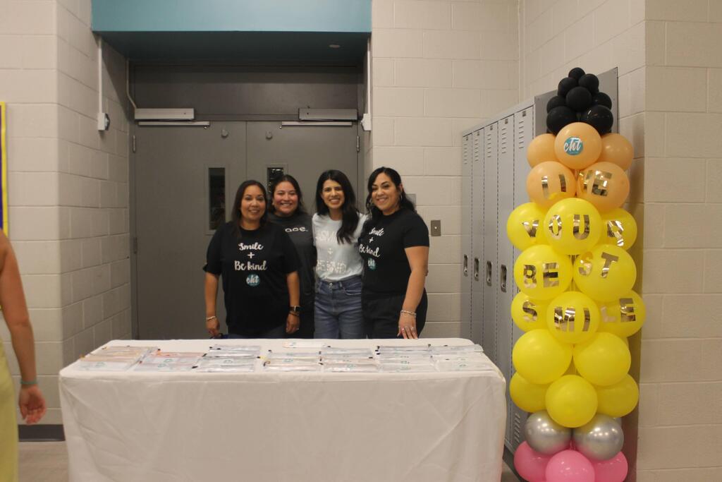 Four staff members smile together behind a table