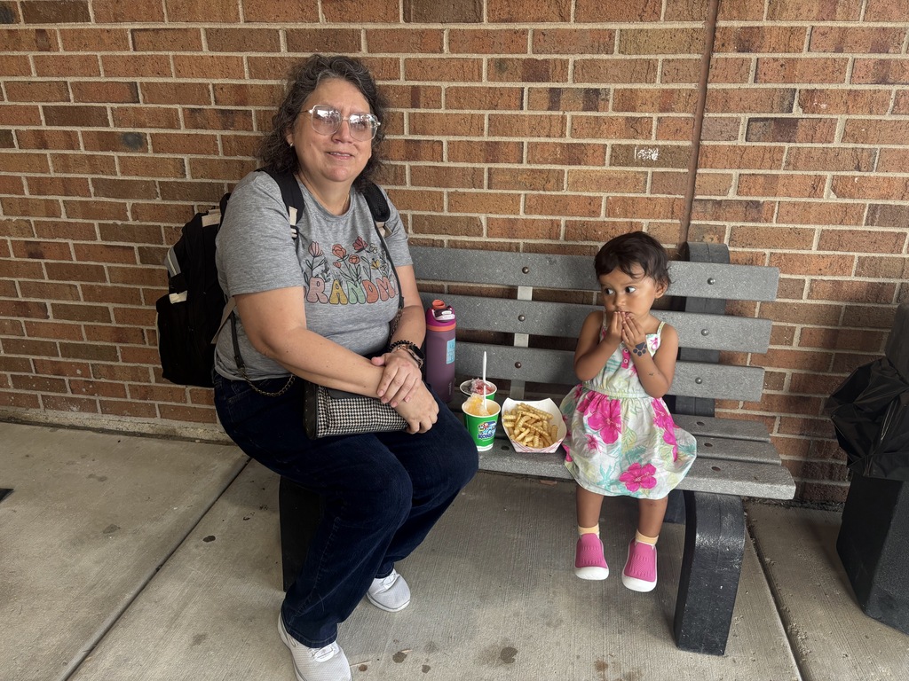 A young student and her grandmother sit on a bench together