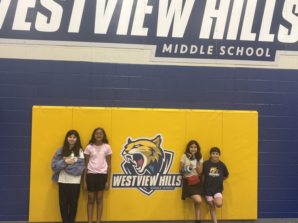 Four girls pose together in front of the Westview Hills logo in the gym
