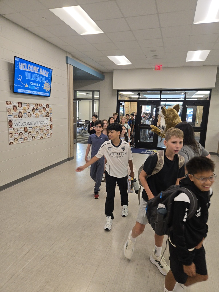 Students high five the Westview Hills mascot while walking in the hallway