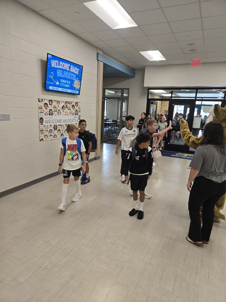 Students high five the Westview Hills mascot while walking in the hallway
