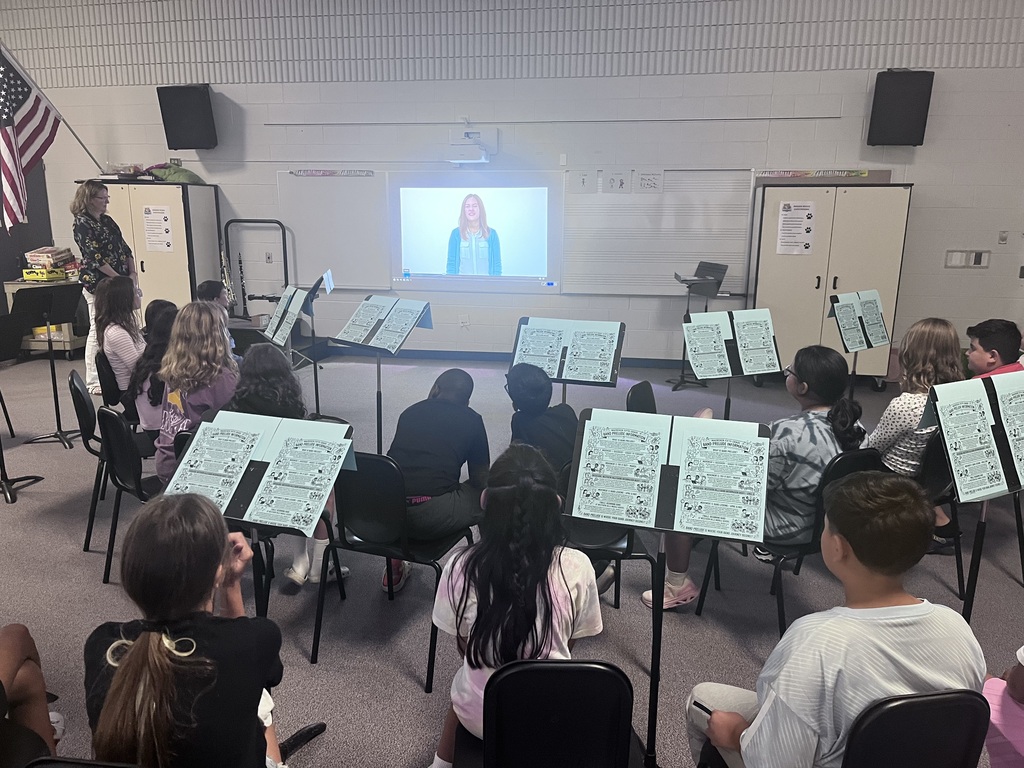 Students sit in chairs in the band classroom with music sheets