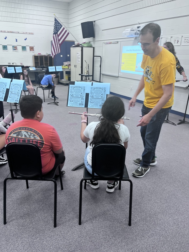 A teacher helps a student who is playing a woodwind instrument