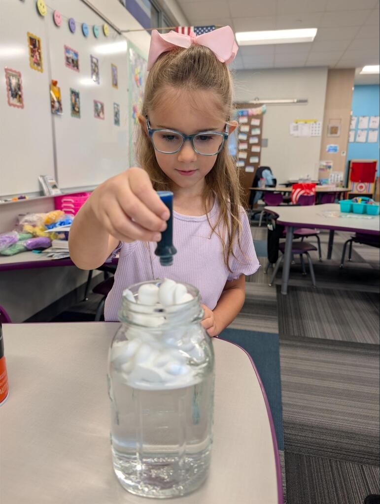 student adding food coloring to jar with water and shaving cream