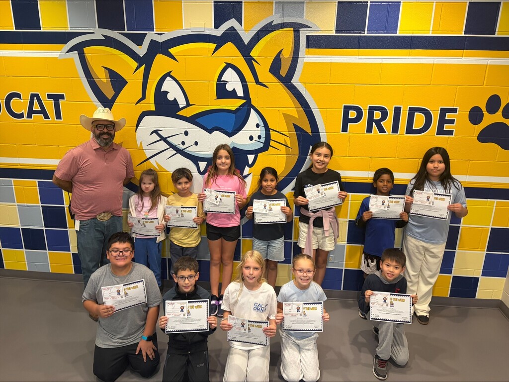 students with awards standing in front of wildcat pride wall