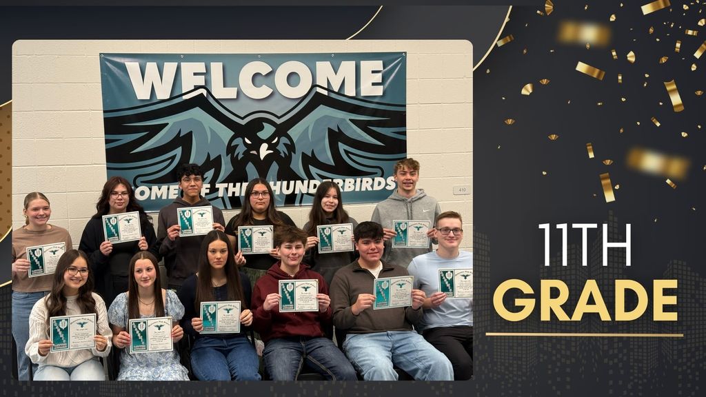 Group of 11th grade students holding certificates and posing together in front of a Thunderbird banner for academic awards recognition.
