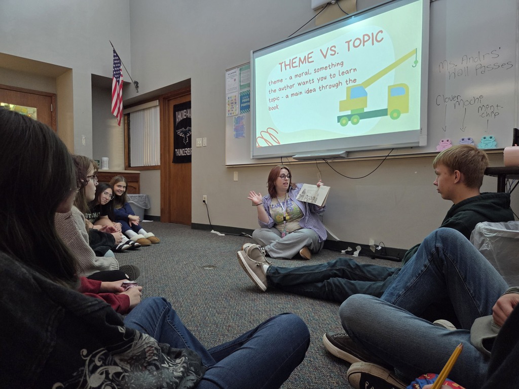 Students sitting on the floor listening to the teacher read a story.