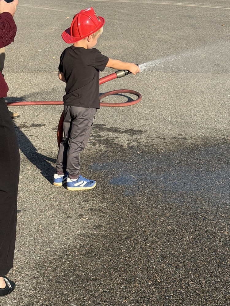 child spraying water from a fire hose