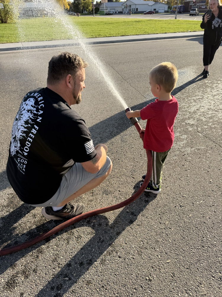 child spraying water from a fire hose