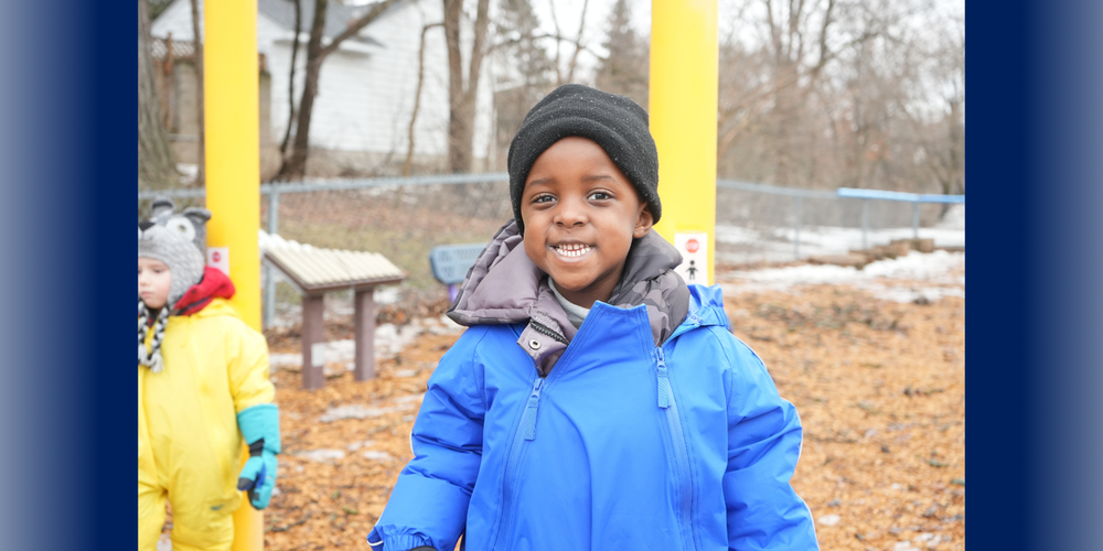 Preschool student wearing blue rain suit