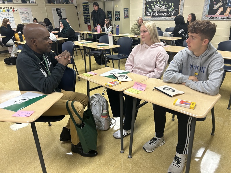 students talk to teacher at table