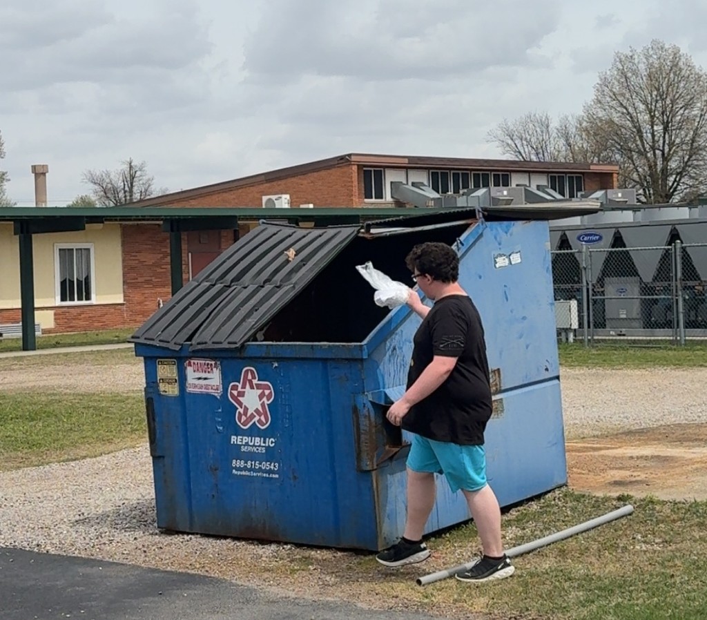 Student throwing trash away in bin