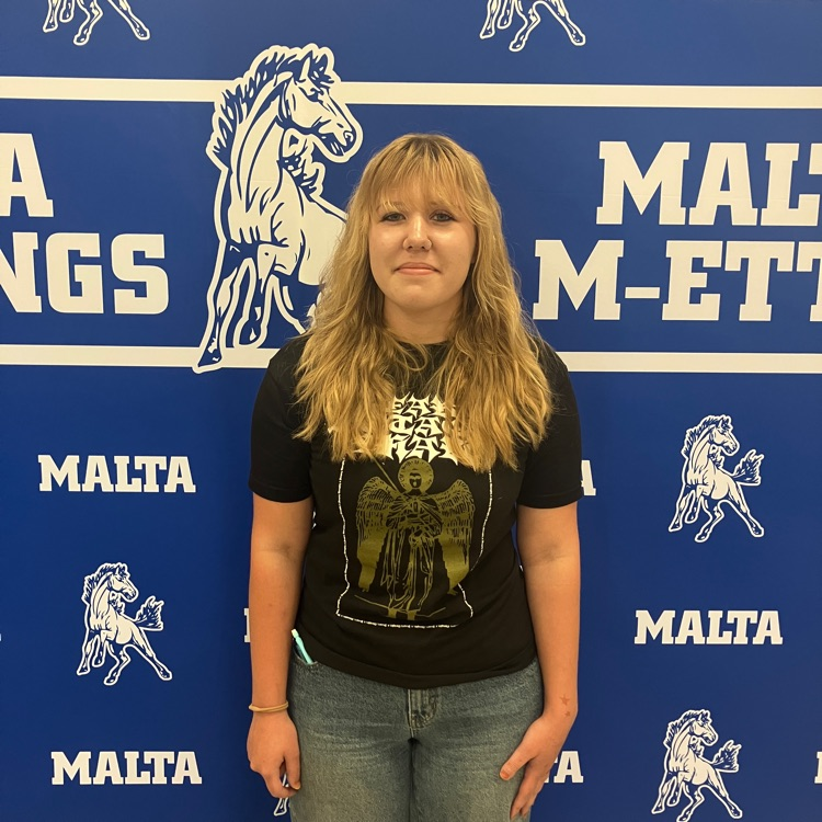 student standing in front of a backdrop that is blue and white