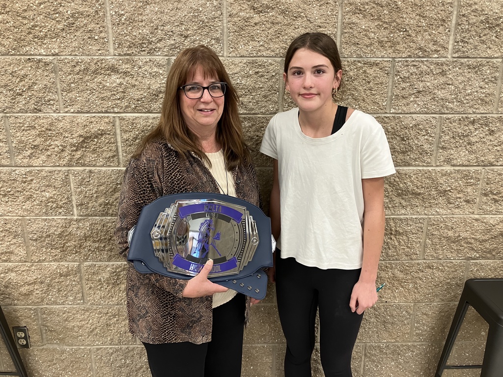 teacher holding an award presented by a student. 