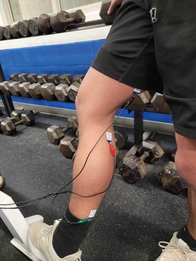 Wires attached to a student's leg to read the electrical activity of the muscles.
