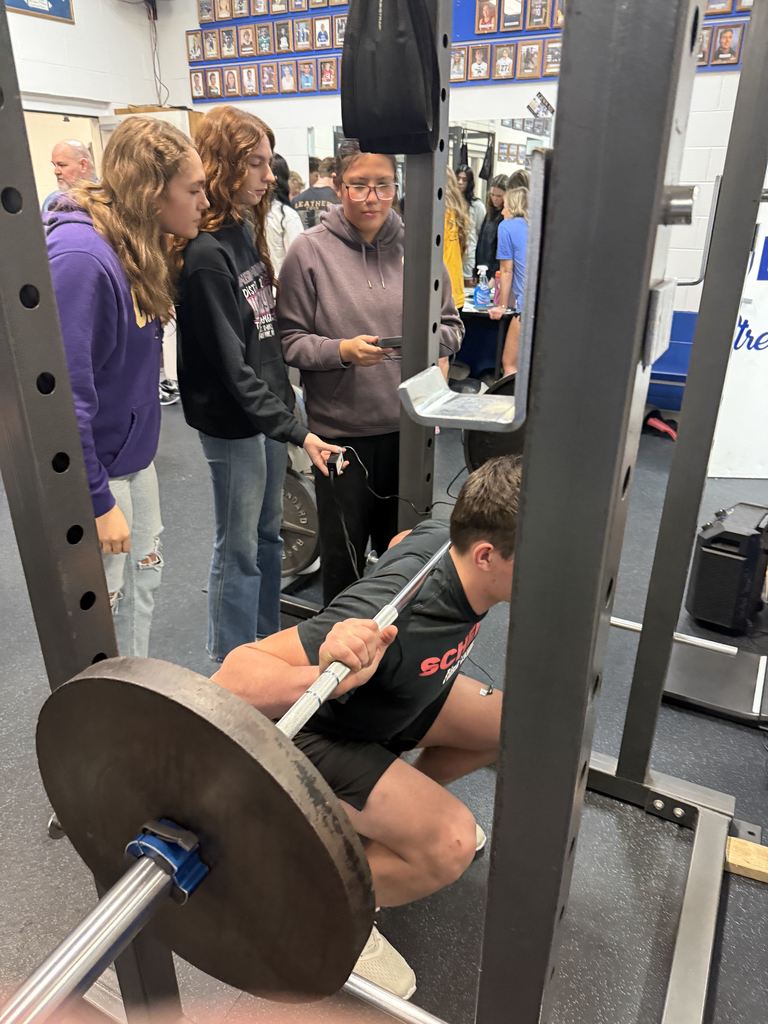 Three student measuring muscle activity of a person performing a squat.