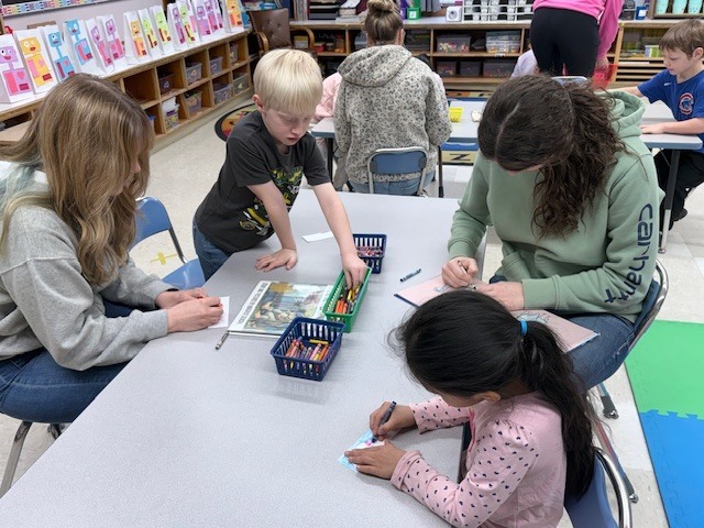 NHS members read to Mrs. Ost and Mrs. Tuss's kindergarten students. 