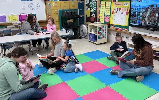 NHS members read to Mrs. Ost and Mrs. Tuss's kindergarten students. 