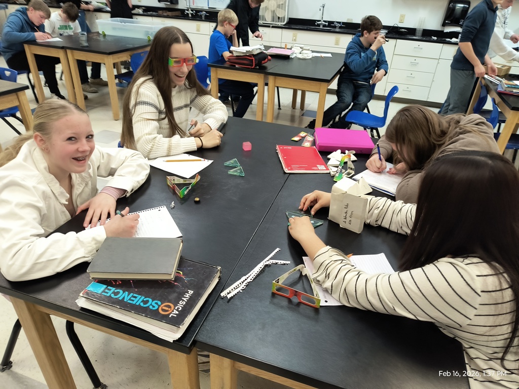 Students using prisms and diffraction glasses to observe changes in light waves.