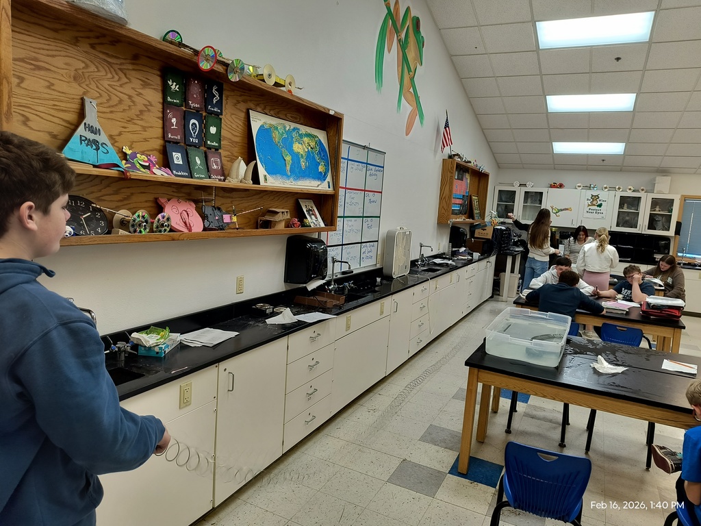 Students using a metal slkinky to observe how waves carry energy through a medium.