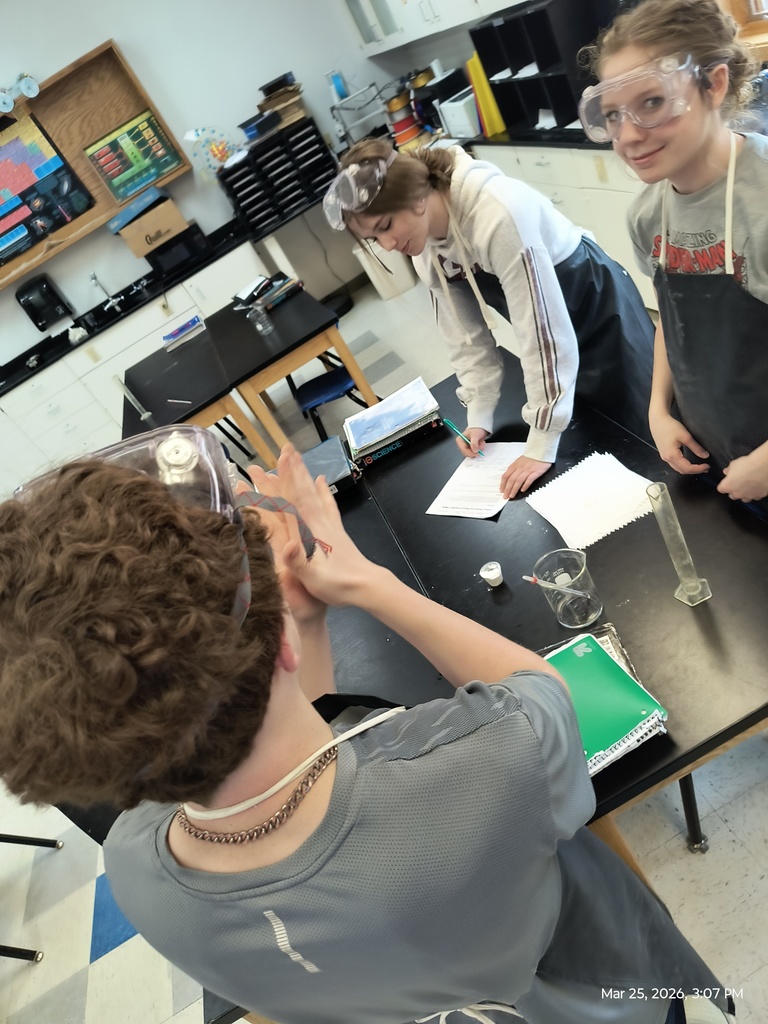 Three students getting ready to see if their white powder reacts with vinegar.