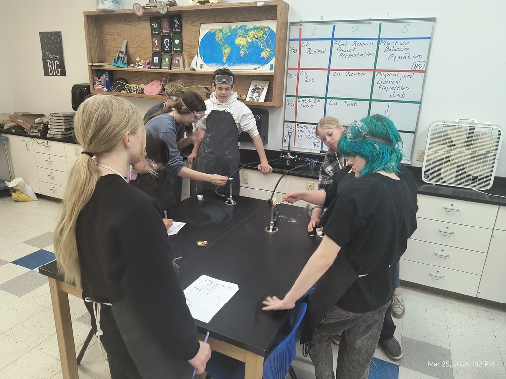 Two groups of students surrounding bunsen burners to see if their substances are flammable or not.