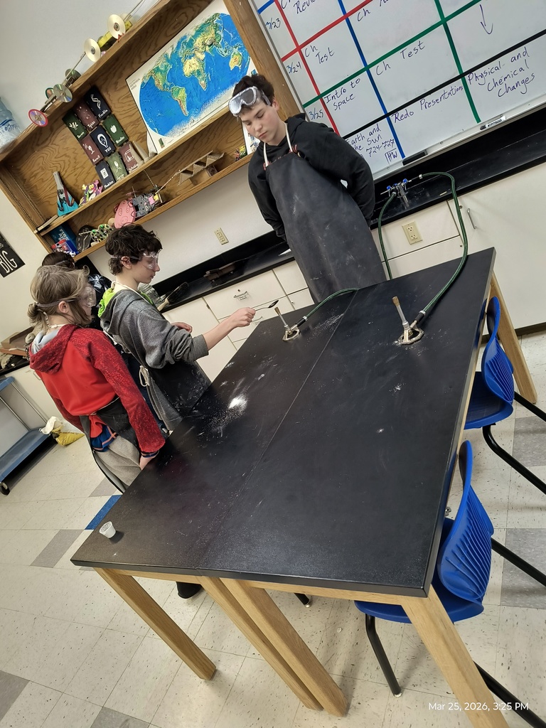 Three students watching to see if the white powder they are testing is flammable or not.
