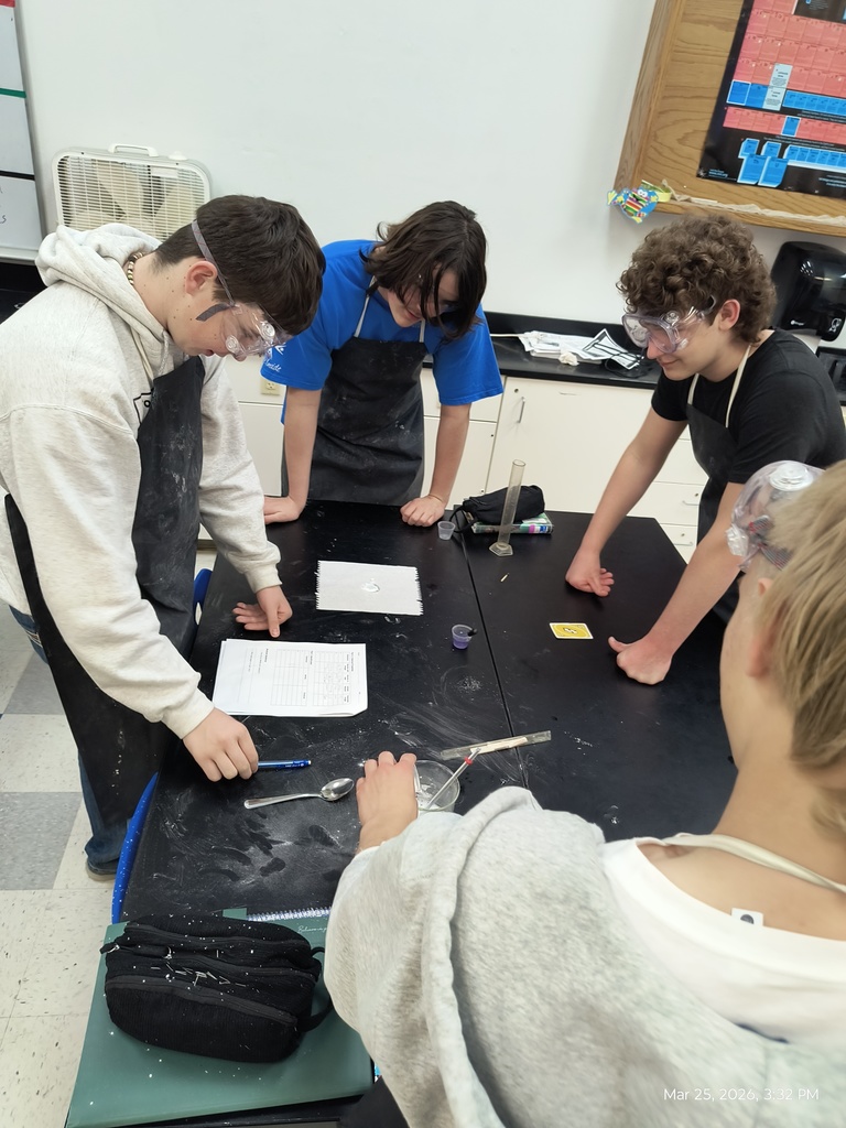 A group of students huddled around a white powder, ph indicator, and a yellow uno reverse card.