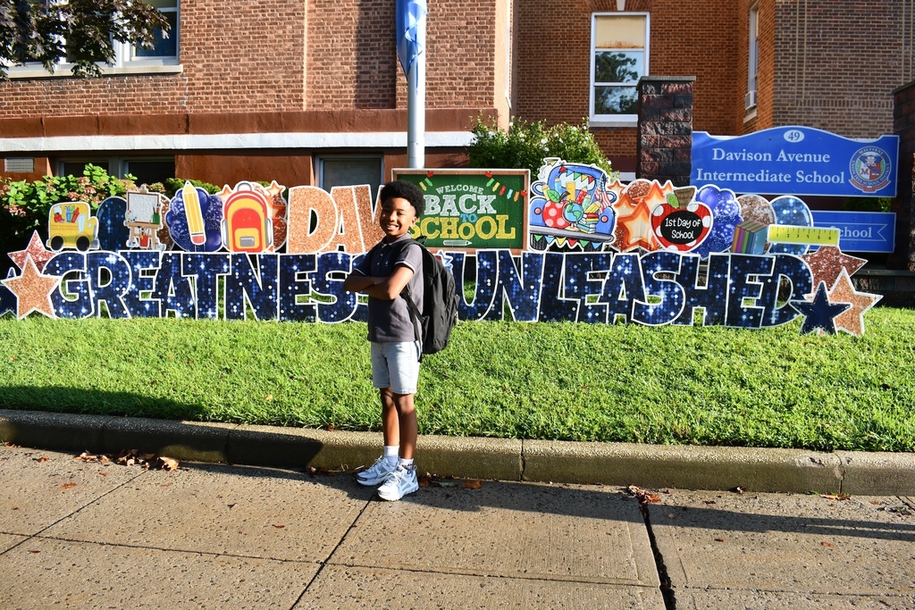 Student in front of sign on first day of school