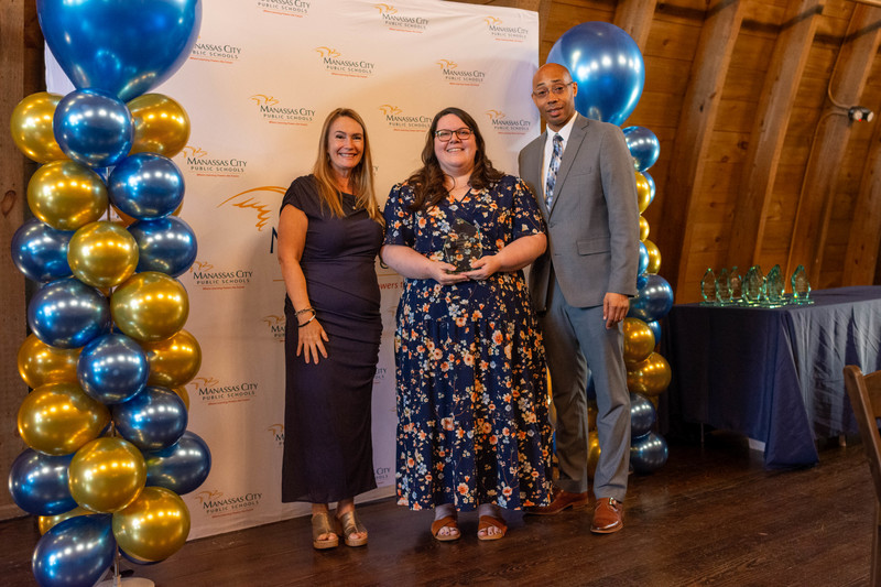 Chair Jill Spall, Taylor Mosser and Dr. Newman on MCPS backdrop surrounded with blue and gold balloons