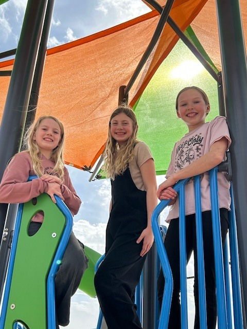 5th graders on the playground orange and green flags on the top of playground 
