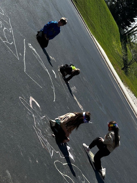 Kindergarten buddies with 3rd graders outside playing with chalk on the blacktop