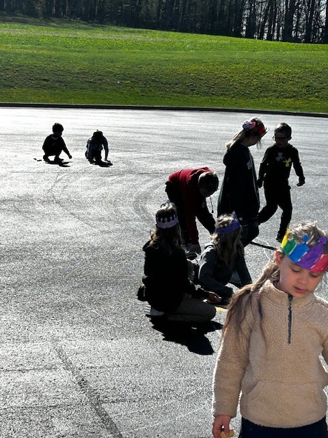 Kindergarten buddies with 3rd graders outside playing with chalk on the blacktop