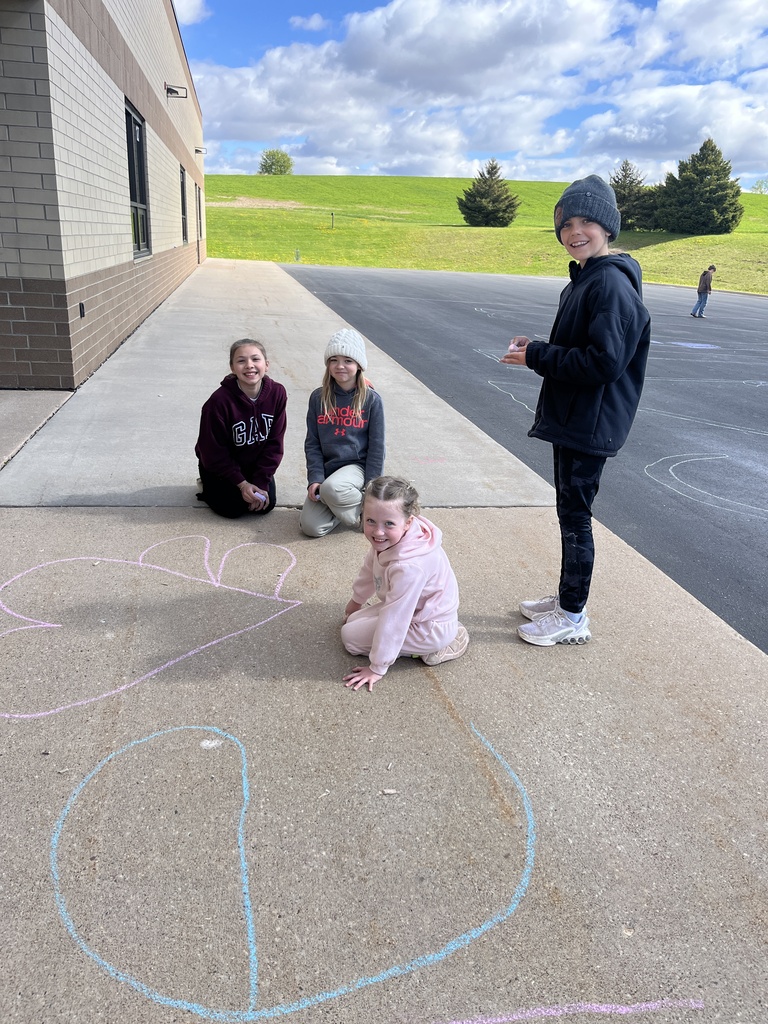 4th grade and kindergarten students outside playing with chalk on the cement