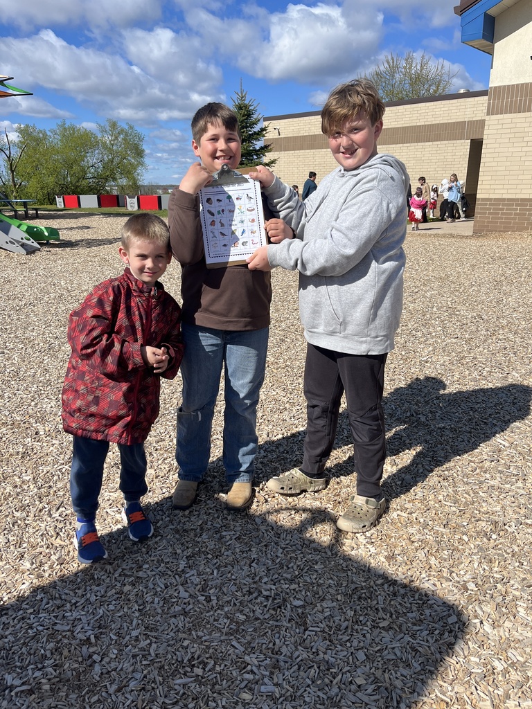 4th grade and kindergarten students outside participating in a scavenger hunt playground in the background