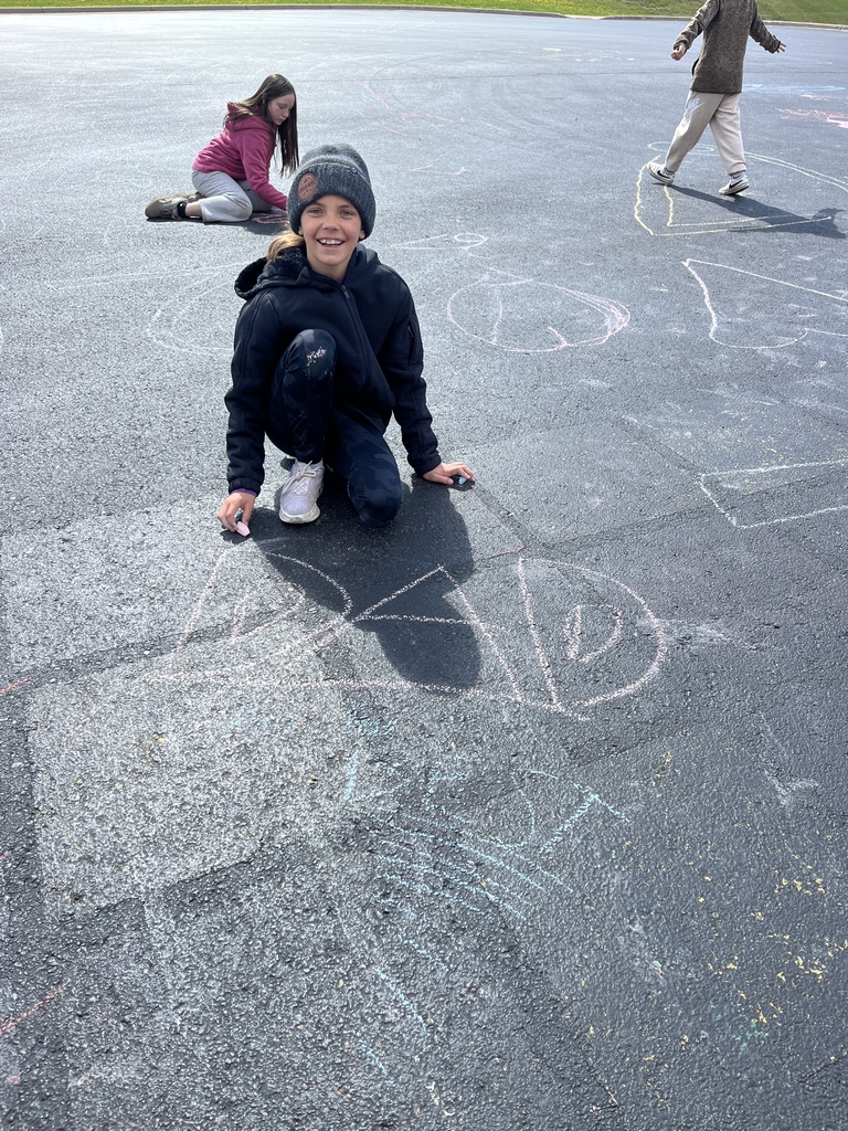 4th grade and kindergarten students outside playing with chalk on the cement