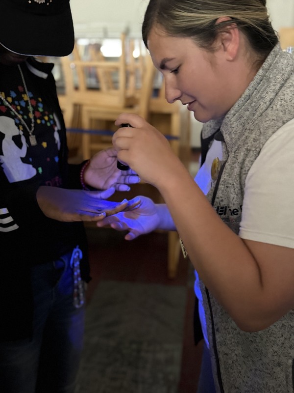 Students hands are checked under black light after hand washing activity