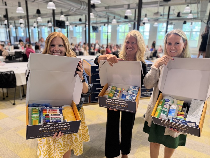SNHU and district leadership with  boxes of donated school supplies