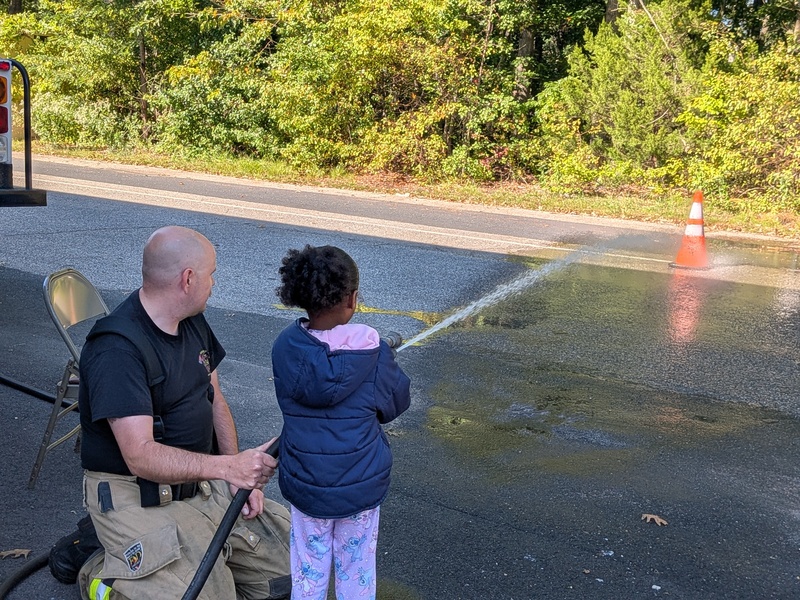 A firefighter supervises MTES students using a fire hose