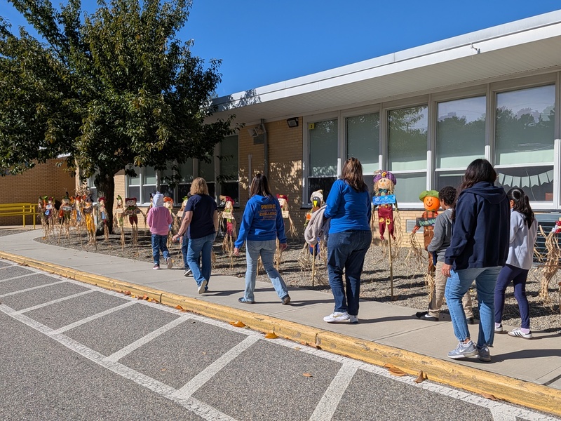 WES staff and students walking by scarecrows