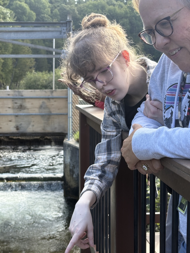 a student looking into the water and pointing at fish